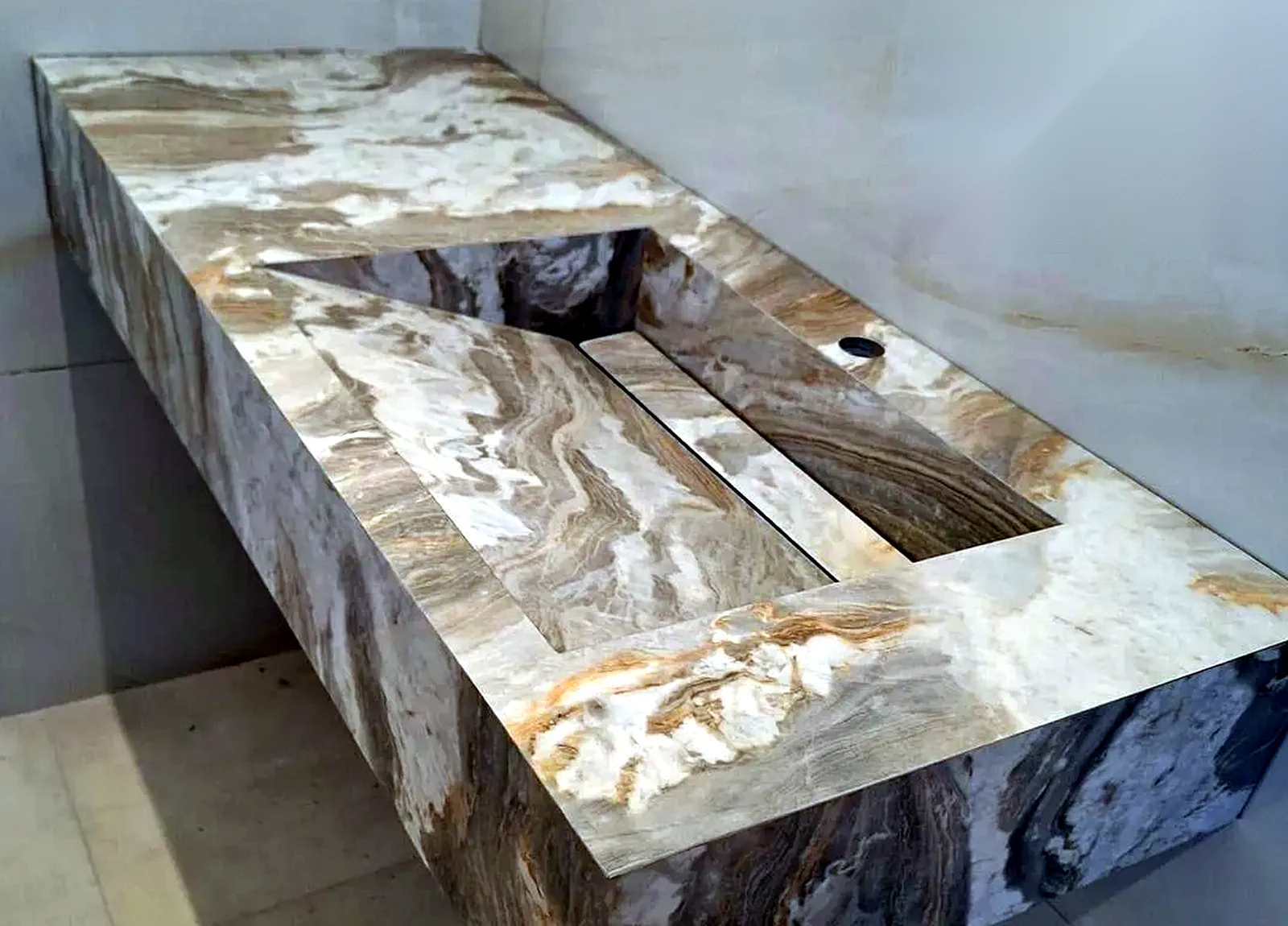 Close-up of stone-effect porcelain sink fabrication showing the mitred basin and waste detail