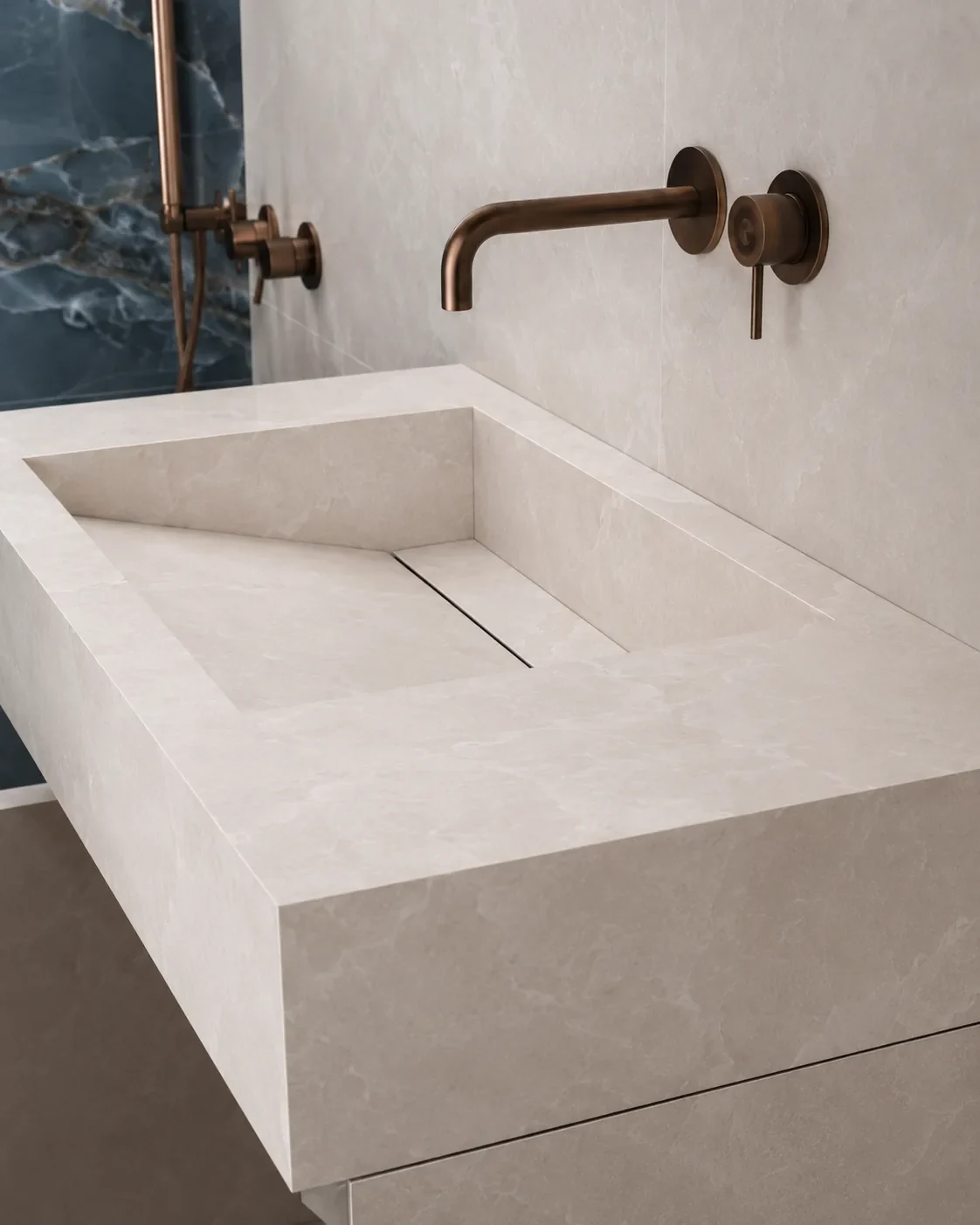 Close view of the integrated mitred porcelain sink, bronze tap mounted on the wall and beige porcelain with a marble pattern.